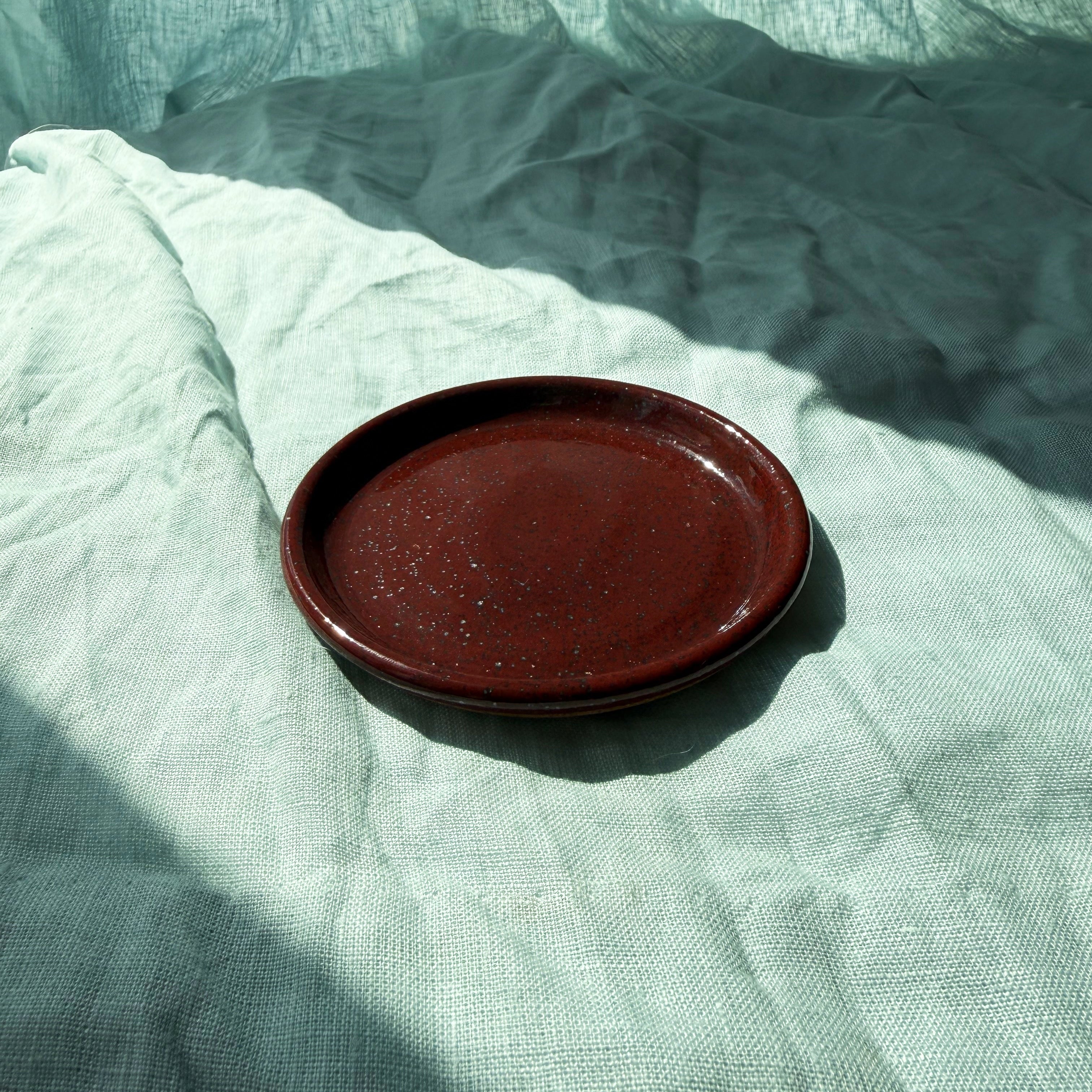 Maroon ceramic dish on textured blue fabric