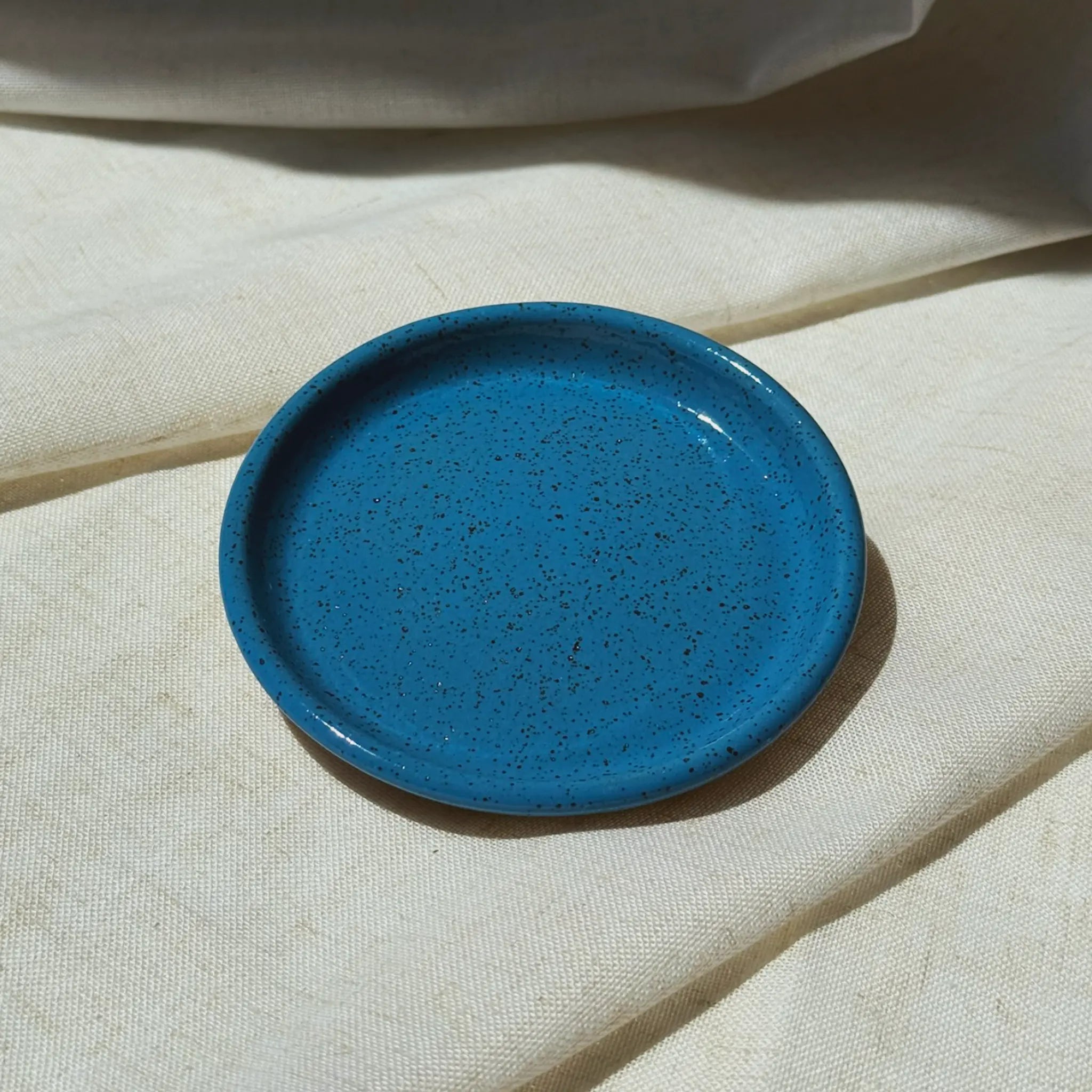 Blue ceramic plate on a beige fabric background