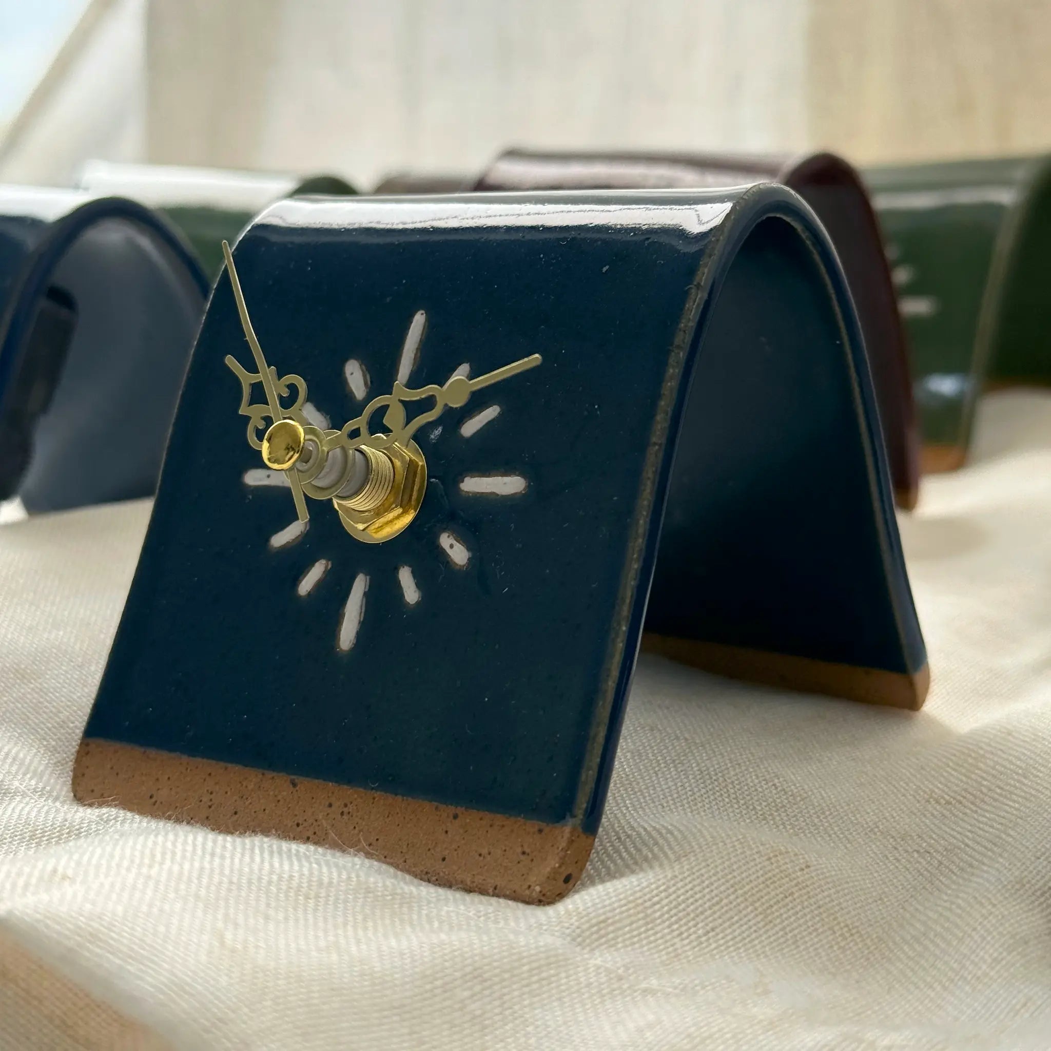 Blue ceramic clock with gold hands on a beige fabric background