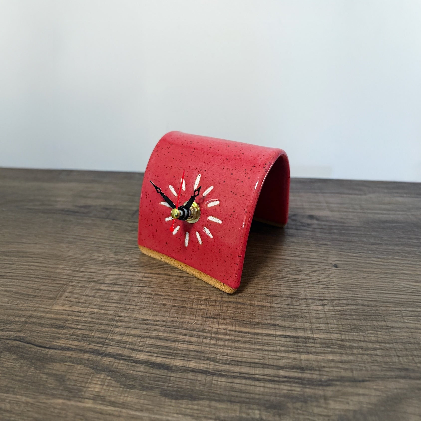 Red ceramic desk clock on a wooden surface with a white background